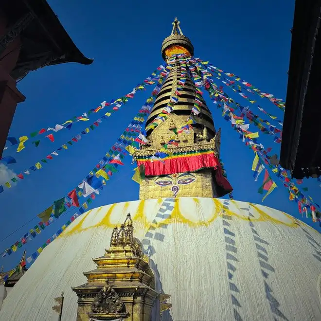 Boudhanath Stupa with prayer flags against a blue sky